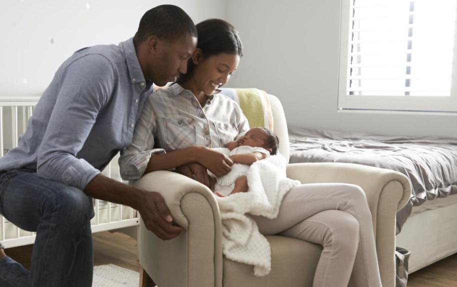 Image of two people holding an infant/newborn.