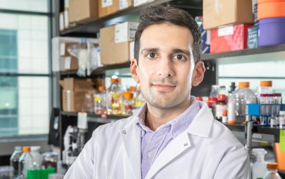Image of Columbia Professor Santiago Correa standing in a laboratory in front of shelves with lab supplies.