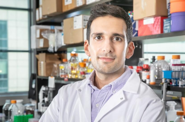 Image of Columbia Professor Santiago Correa standing in a laboratory in front of shelves with lab supplies.